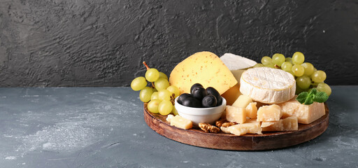 Plate with different types of tasty cheese and grapes on table