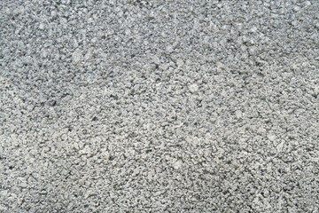 A textured background of a rough, unfinished cement wall. This horizontal view highlights the raw, gritty surface before it is smoothed out for construction.
