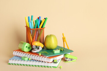 Green apple and school supplies on beige background