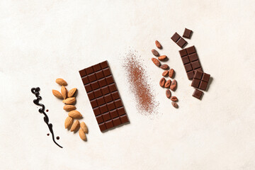 Sweet chocolate with almond nuts, cocoa beans and powder on white background