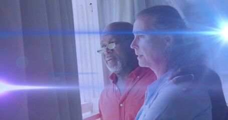 Black man and White woman standing by balcony railing at home, with tinted spectacles, lens flare