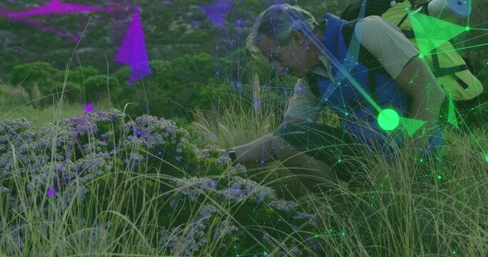 Inspecting purple flowers, hiker kneeling in meadow, with yellow backpack, data overlay, copy space
