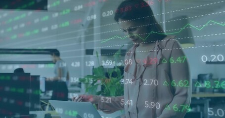 Typing businesswoman standing in open plan office with laptop, potted plant, monitors, copy space