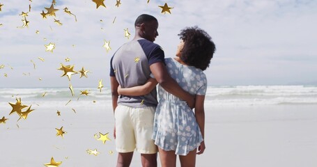 Naklejka premium Standing adult couple holding waists at sandy beach shoreline, with decorative golden star shapes