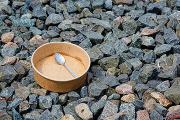 Deep paper plate and spoon on rocks in a quiet open area