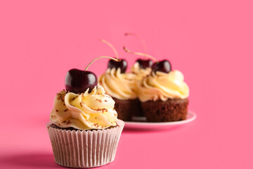 Plate with sweet cherry cupcakes on pink background