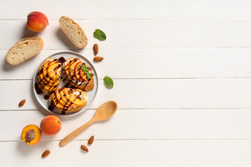 Plate of peach bruschetta with ricotta, mint and almond nuts on white wooden background
