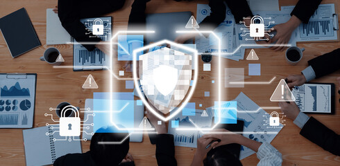 Professionals collaborate on data security strategies, using charts and graphs, with digital lock icons and a shield concept overlaid on their workspace. Trope