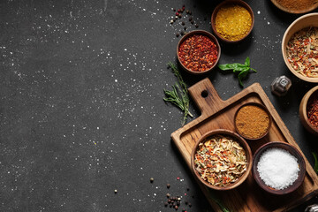 Composition with wooden board and bowls of fresh aromatic spices on dark background
