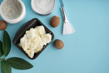 Composition with shea butter, nuts and cosmetic products on color background