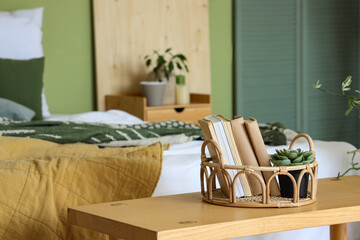 Tray with books and plant on wooden bench in bedroom