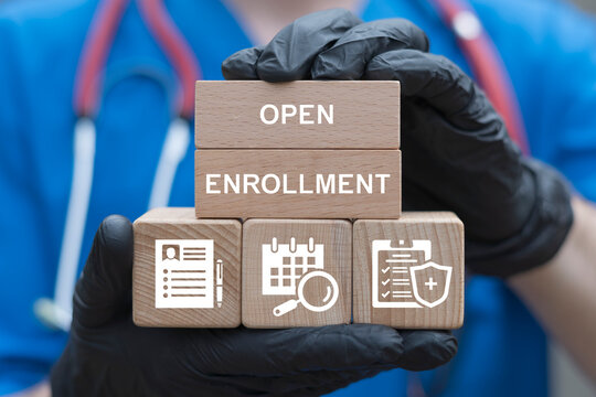 Doctor holding wooden blocks with icons sees the inscription open enrollment. Open Enrollment Health Сare Insurance Business concept.