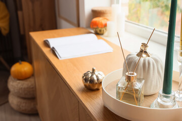 Book, reed diffuser and pumpkins on chest of drawers in bedroom