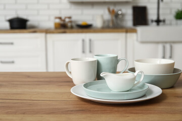 Porcelain plates, cups and gravy boat on wooden counter in kitchen