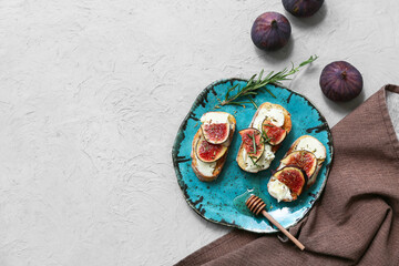 Plate of delicious fig bruschetta with ricotta cheese and rosemary on white background