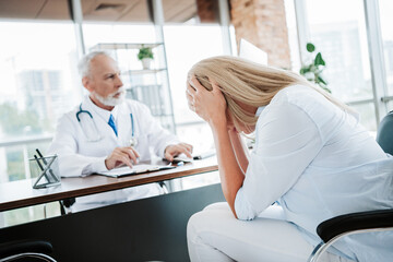Obraz premium Woman at a medical consultation looking stressed while a professional doctor discusses health concerns in a modern clinic