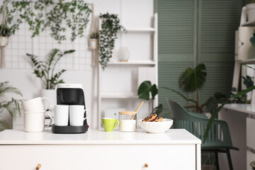 Coffee machine with cups and cookies on commode in office