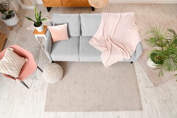 Interior of living room with sofa, knitted plaid and chair, top view
