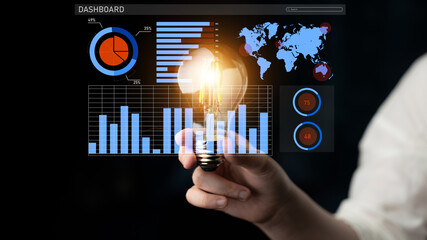 A hand holding a light bulb symbolizes innovative ideas, set against a digital dashboard displaying graphs and analytics, perfect for business and strategy themes. Impute
