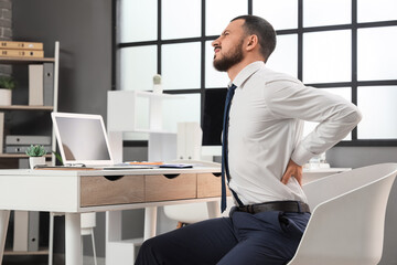Fototapeta premium Young businessman suffering from back pain at table in office