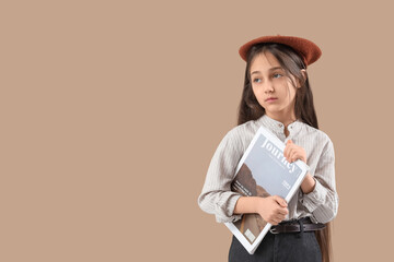 Stylish girl in beret with magazine on beige background