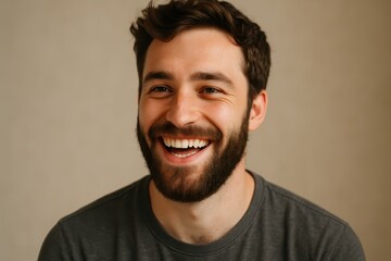 Obraz premium Candid portrait of laughing young man with long hipster beard and sparkling eyes natural light authentic friendly expression against simple studio background