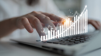 A business professional analyzes data trends using a laptop, with an overlay of a digital graph depicting significant financial growth and strategic insights. Impute