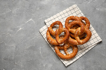 Napkin with tasty pretzels on grey grunge background, closeup