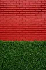 A vibrant red brick wall meets a lush green grassy area, creating a striking contrast.