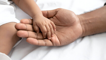 Tiny hand of newborn baby holding fathers finger.