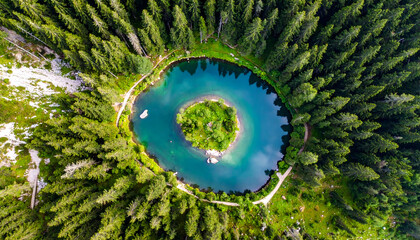 Aerial view of a serene lake surrounded by lush green forest.