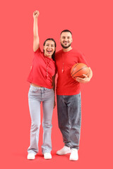 Young couple watching basketball game on red background
