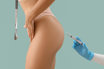 Doctor's hand injecting woman on green background, closeup. Weight loss concept