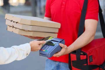 Male courier receiving payment for pizza from customer outdoors, closeup