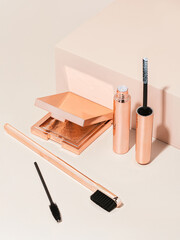 Rose gold eyebrow wax lamination kit on tan background with shadows 