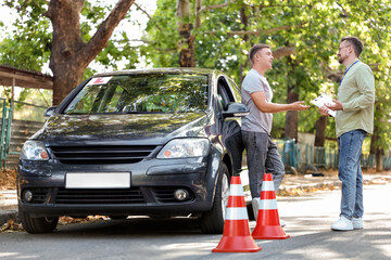 Young man passing driving license test with instructor on street