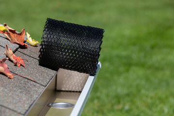 Installing gutter guard mesh screen on rain guttering. Home maintenance, yardwork and roof damage concept