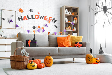 Interior of living room decorated for Halloween with sofa, shelf unit and pumpkins
