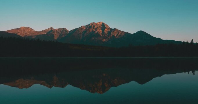 Time lapse of sunrise lights glowing over pine forest at Pyramid Lake located at the foot of Pyramid Mountain in Jasper National Park, Alberta, Canada.