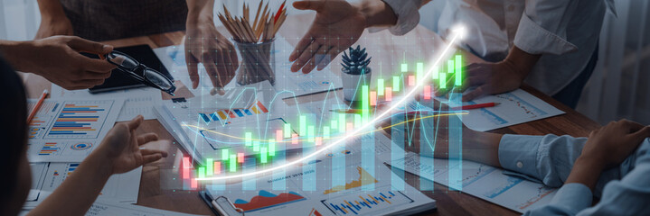 A dynamic business meeting focused on growth, featuring professionals collaborating over charts and graphs that highlight progress in a modern workspace. Axiom