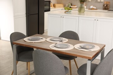 Kitchen interior with dining table, place setting and grey chairs