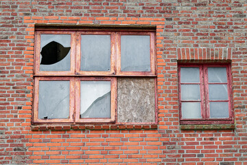 Red brick facade with six worn red wooden windows in a row