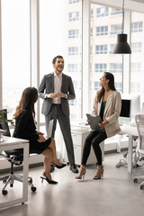 Fototapeta premium Small team of three diverse coworkers standing in office