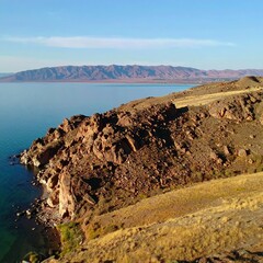 Lakeside rocky outcrop, distant mountains