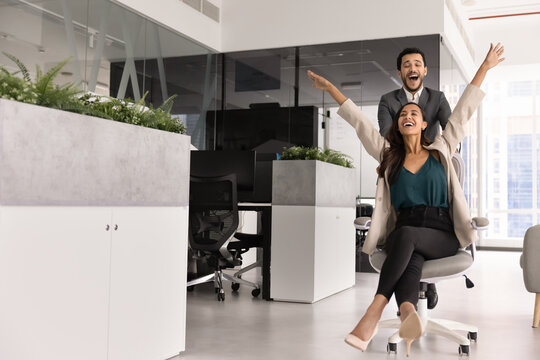 Cheerful young diverse business coworkers having fun in office space