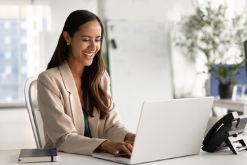 Cheerful young New Zealander manager woman working at computer