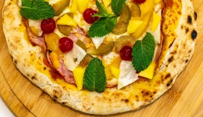 The iconic, wonderful, and unique California pizza, made with Canadian pork tenderloin and tropical fruits—pineapple, mango, fig, peach, and cherries—garnished with fresh mint leaves. 