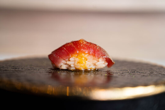 Akami (lean tuna) nigiri sushi, a classic Japanese dish from an Omakase course, served on a black plate.