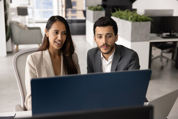 Two young diverse product managers working together at computer