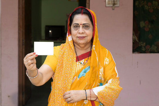Portrait of Indian old woman showing showing unique identity card at village. Indian senior rural woman showing Aadhar card at home. Concept of rural woman empowerment in india.